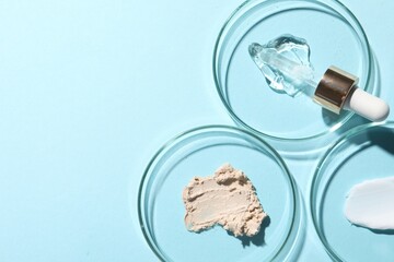 Pipette, cosmetic serum and petri dishes with samples on light blue background, flat lay. Space for text