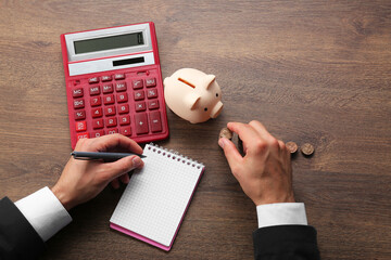 Budget planning. Businessman with notebook calculating at wooden table, top view