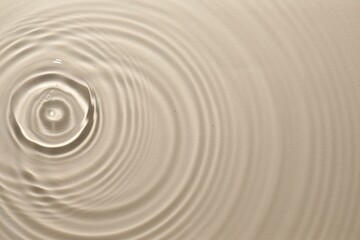 Fototapeta na wymiar Rippled surface of clear water on beige background, top view