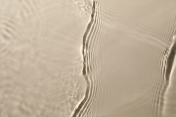 Rippled surface of clear water on beige background, top view