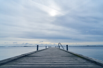 Wooden pier or dock on sea water in morning light