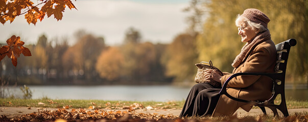 Senior lady sitting on wooden bench in autumn forest or park.