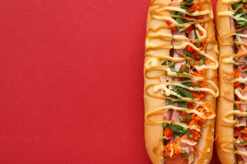 Delicious hot dogs with bacon, carrot and parsley on red background, top view. Space for text
