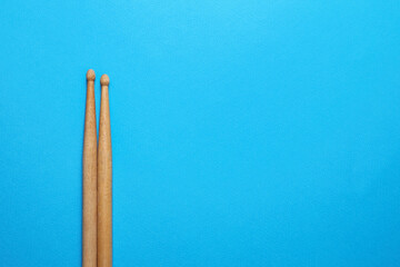 Two wooden drum sticks on light blue background, top view. Space for text