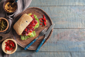 Delicious sandwich with bresaola, lettuce and cheese served on light blue wooden table, flat lay. Space for text