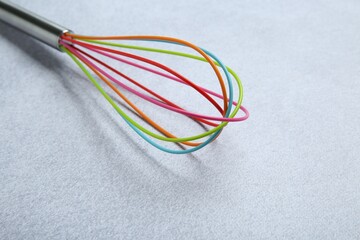 Bright whisk on gray table, closeup. Space for text