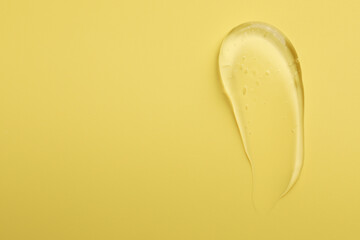 Smear of clear cosmetic gel on yellow background, top view. Space for text