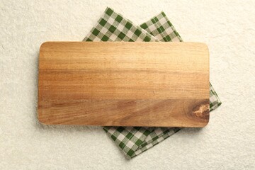 Wooden cutting board and napkin on beige table, top view. Space for text