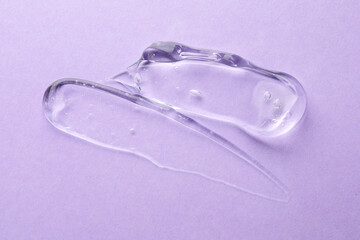 Clear cosmetic gel on violet background, top view