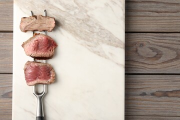 Delicious sliced beef tenderloin with different degrees of doneness on wooden table, top view. Space for text