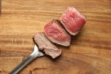 Delicious sliced beef tenderloin with different degrees of doneness on wooden table, top view