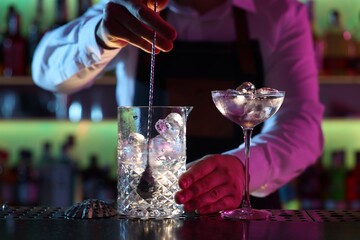 Bartender making fresh alcoholic cocktail at counter in bar, closeup