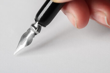 Woman with fountain pen above white paper, closeup