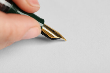 Woman with fountain pen above white paper, closeup. Space for text