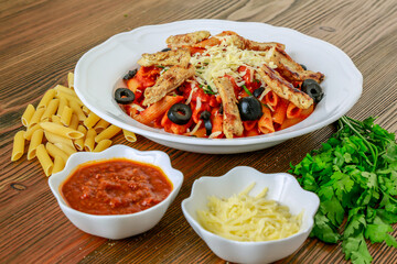 Tomato sauce pasta with chili sauce, chicken, olives and coriander served in dish isolated on table top view of arabic food