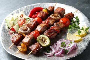 Delicious shish kebabs with vegetables on grey textured table, closeup