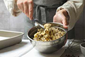 Woman making chocolate chip cookie dough at table, closeup