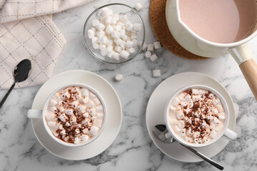 Aromatic hot chocolate with marshmallows and cocoa powder served on white marble table, flat lay