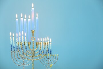 Hanukkah celebration. Menorahs with burning candles on light blue background, space for text