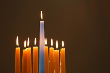 Hanukkah celebration. Burning candles on brown background, space for text