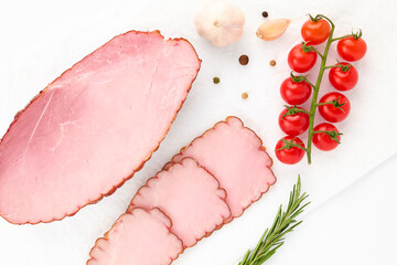 Pork balyk slices on white background isolated decorated sprig of fresh cherry tomatoes, sprig of parsley, sweet peas and garlic cloves. Top view for your design. Healthy food. Protein, vitamins
