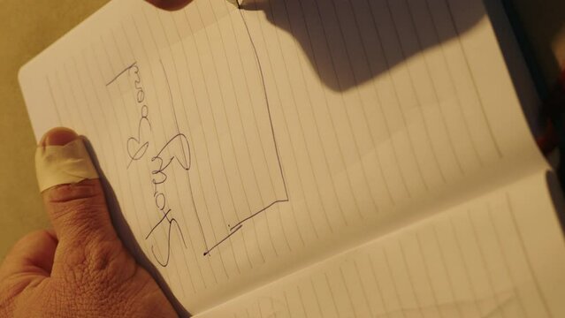 Close up view of man's hands, preparing for exam and making notes in notebook. Taking notes, putting signature in corporate papers.
