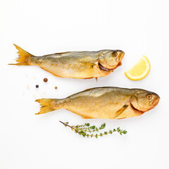 Cold smoked sea fish carcass close up isolated on white background decorated with fresh sprig of thyme, lemon, crystals of coarse pink salt, black peppercorns. Salty snacks. Omega3