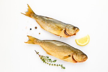 Cold smoked sea fish carcass close up isolated on white background decorated with fresh sprig of thyme, lemon, crystals of coarse pink salt, black peppercorns. Salty snacks. Omega3