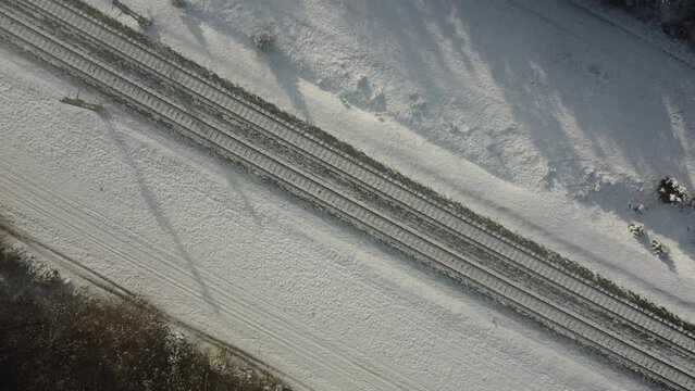 Top view of train track rails crossing through snowy forest in winter near Munich