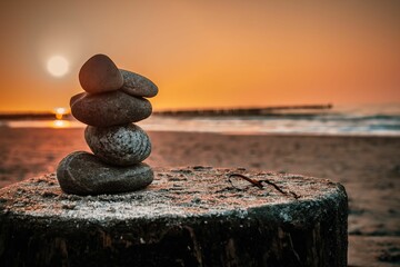 Zen-like stack of stones standing in harmony against the radiant sunset at the Baltic Sea