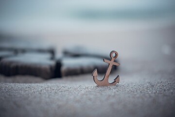 Small anchor emblem restinf upon the sandy shores of the Baltic Sea coast in Germany