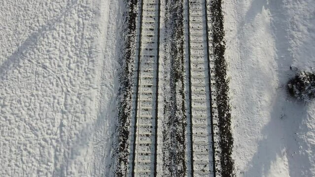 Top view of train track rails crossing through snowy forest in winter near Munich