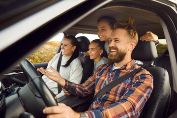 Portrait of happy laughing smiling family of four with children riding in modern car traveling by automobile together enjoying vacation or road trip on weekend. Family travel concept. - Powered by Adobe
