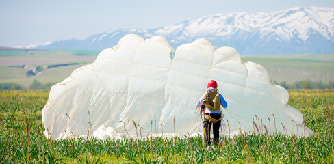 Skydiving. The landed parachutists collect the parachute canopy on the ground. Extreme sport and...