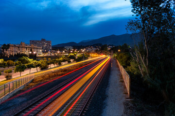 Obraz premium Long exposure shows light trails left behind by a close-distance train.