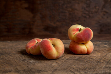 Several saturn peaches or flat peaches on wooden background..