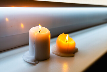 Fototapeta na wymiar Two burning candles on windowsill.Two candles on a windowsill at home interior.Closeup.