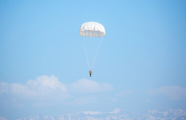 Skydiving. Flying parachutists against the background of the blue sky and mountains. Extreme sport and entertainment.