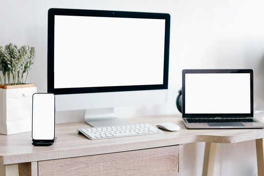 Mockup of laptop computer and mobile phone with white blank screen on office table