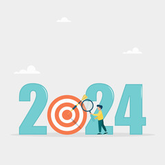 Analysis and development of business strategies for the new year 2024, planning and setting business goals. The guy looks through a magnifying glass in search of a goal for the new year.
