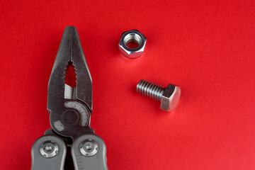 Multi Tool Pliers with Nut and Bolt on a Red Table Surface - 688595647