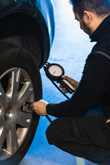 Hands of a mechanic inflating a car tire in his workshop