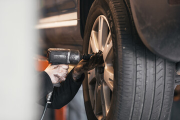 Mechanic changing a car wheel with tools in his workshop