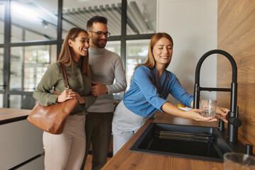 Female shop assistant helping young couple choose new kitchen faucet