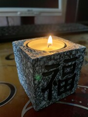 Burning candle in a square candlestick with hieroglyphs