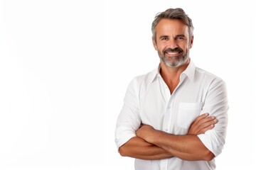 Smiling middle-aged man with folded arms and a deadpan expression posing in front of a white...