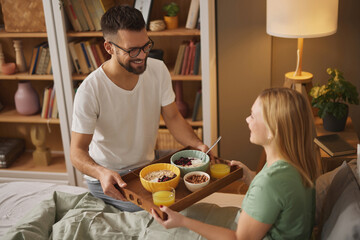 Young man bringing surprised woman breakfast in bed