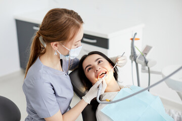Beautiful young woman doing tooth examination in the dental office. Portrait of smiling girl on a dental chair in dentistry