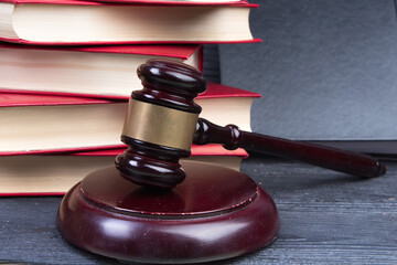 Law concept - Open law book with a wooden judges gavel on table in a courtroom or law enforcement...