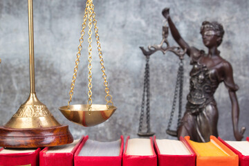 Law concept - Open law book, scales, Themis statue on table in a courtroom or law enforcement office.